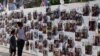 FILE - A woman and child walk by a wall with pictures of people held in Gaza after they were kidnapped from Israel by Hamas gunmen. A group of family members of hostages is asking prosecutors at the International Criminal Court to bring charges against Hamas leaders.