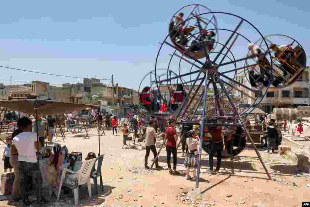 Children sit in an amusement ride on the first day of the Muslim feast of Eid al-Adha in Syria&#39;s rebel-held city of Binnish in the northwestern province of Idlib.