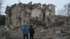 Local residents stand among debris of a residential building partially destroyed by a missile attack in the town of Selydove, Donetsk region, Ukraine, on Feb. 8, 2024.