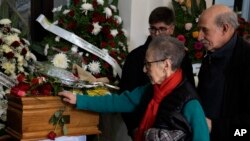 A woman places a rose on the coffin that contains the remains of Amelia Sanjurjo sits inside a hearse during her funeral service at the University of the Republic, in Montevideo, Uruguay, June 6, 2024. 
