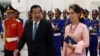FILE - Myanmar's State Counsellor Aung San Suu Kyi (R) and Cambodia's Prime Minister Hun Sen walk past the honor guard during her visit at the Peace Palace in Phnom Penh, April 30, 2019.