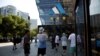 FILE - A man takes a photo of an Adidas flagship store at a shopping complex in Beijing, China, June 14, 2023.