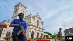 A navy sailor and police officers stand guard outside St. Anthony's church on the fifth anniversary of the Easter Sunday suicide attacks, in Colombo on April 21, 2024. 