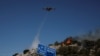A plane drops water as firefighters try to extinguish a wildfire near the town of Koropi, Greece, June 19, 2024.