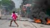 A woman carrying a child runs after gunshots were heard in Port-au-Prince, Haiti, on March 20, 2024. 