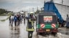 A Kenyan firefighter gives directions to commuters as residents inspect a road heavily affected by floods following torrential rains in Kitengela, May 1, 2024.