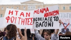 Protesters hold banners during a demonstration in front of the parliament building, following the fatal collision of two trains, in Athens, March 12, 2023. The banners read 'They were students. The train car sank with students' blood.'