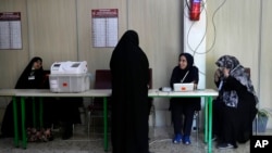 Staff members of a polling station attend to their stations during the parliamentary runoff elections in Tehran, Iran, May 10, 2024. 