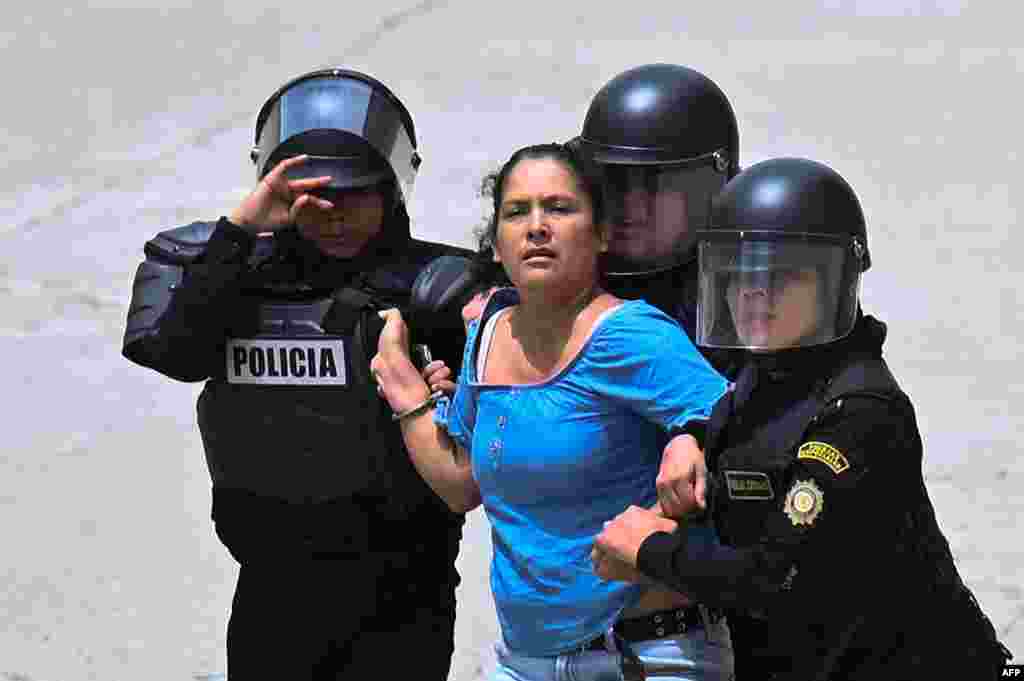 A woman is arrested as voters are dispersed by security forces outside a polling station which remains closed following alleged threats and irregularities during general elections, in San Jose del Golfo, on the northern outskirts of Guatemala City, June 25, 2023.&nbsp;