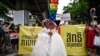 FILE - A same-sex couple poses in wedding dresses as members of the LGBTQ community take part in a Pride March in Bangkok on June 5, 2022. 