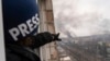FILE - A reporter points at smoke from an airstrike on a hospital, in Mariupol, Ukraine, March 9, 2022. Ukrainian journalist Bohdan Bitik, who was working in Ukraine for La Repubblica, was slain April 26, 2023, by suspected Russian snipers.
