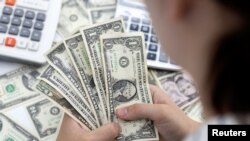 Woman holds U.S. dollar banknotes in this illustration taken May 30, 2022. According to a Prudential Financial survey released, June 24, 2024, women in the U.S. have saved just a third of the amount that men have set aside for retirement.