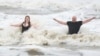 Jeremy Reddout and his daughter, Elexus, enjoy the waves between Murdoch's and Pleasure Pier as rain falls in Galveston, Texas, June 19, 2024.