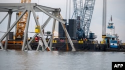 This handout photo shows demolition crews cutting the top portion of the north side of the collapsed Francis Scott Key Bridge into smaller sections for safe removal by crane in the Patapsco River, March 30, 2024. (Kimberly Reaves/US Coast Guard/AFP)
