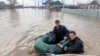 This photo released by the Russian Emergency Situations Ministry on April 6, 2024, shows rescuers wading across a flooded street on their way to evacuate residents in the Orenburg region, southeast of the southern tip of the Ural Mountains, Russia.