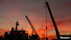 FILE - Workers load equipment onto a truck to be transported to a ship for a delivery to oil rigs, at a port on Malaysia's island of Labuan, Feb. 7, 2012. 