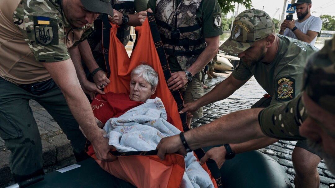 Emergency workers evacuate an elderly resident on a rubber boat from a flooded neighborhood in Kherson, Ukraine, June 7, 2023. 