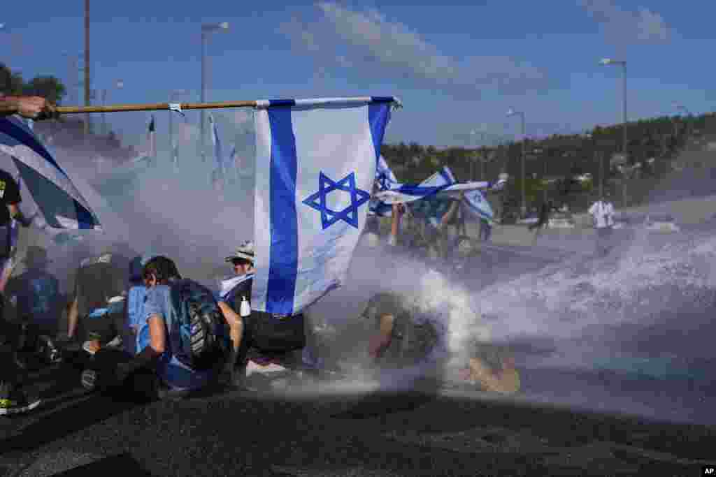 Israeli police use a water cannon to disperse demonstrators blocking a highway leading to Jerusalem during a protest of plans by Prime Minister Benjamin Netanyahu&#39;s new government to overhaul the judicial system.