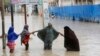 FILE - Women walk through floodwaters after heavy rainfall in Mogadishu, Somalia, Nov. 20, 2023. 