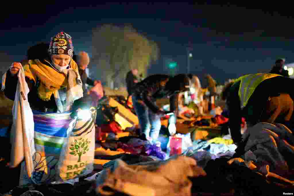 A woman searches through donated clothes after she and her children fled the Russian invasion in Ukraine and crossed the border in Medyka, Poland, Feb. 27, 2022.