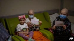 Oncology patients hold up sheets of paper with the words "Stop War" in a basement used as a bomb shelter at the Okhmadet children's hospital in central Kyiv, Ukraine, Monday, Feb. 28, 2022. (AP Photo/Emilio Morenatti)