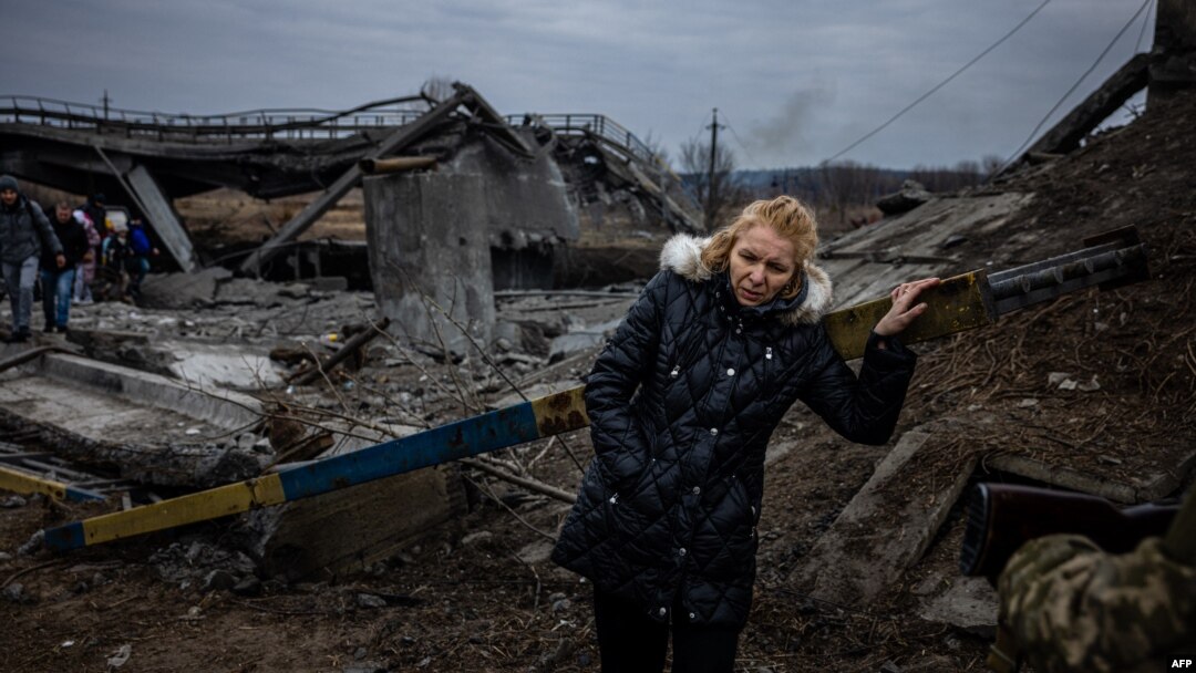 A woman rests after crossing a destroyed bridge as she evacuates from the city of Irpin, northwest of Kyiv, on March 7, 2022.