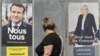 Women walk past campaign posters of French President and La Republique en Marche (LREM) party candidate for re-election Emmanuel Macron (L) and French far-right party Rassemblement National (RN) presidential candidate Marine Le Pen, in Eguisheim, eastern France, April 21, 2022.