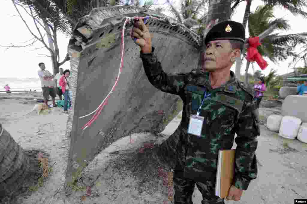 Thai army soldier inspects a piece of suspected plane wreckage which has been found off the coast of southern Thailand in Nakhon Si Thammarat province.