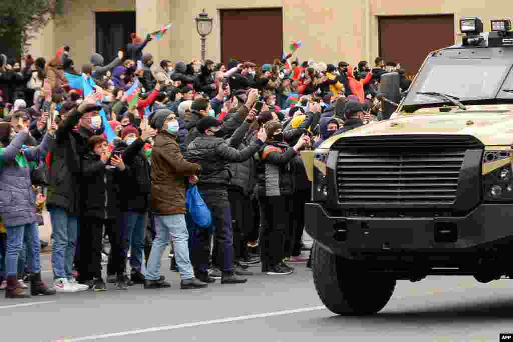 People greet Azerbaijani servicemen riding in military vehicles during a parade marking Azerbaijan&#39;s victory against Armenia in their conflict for control over the disputed Nagorno-Karabakh region, in Baku.