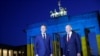 Французький президент Еммануель Макрон та німецький канцлер Олаф Шольц біля освітлених кольорами українського прапора Бранденбурзьких воріт у Берліні 9 травня 2022 р.