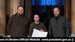 Президент Володимир Зеленський (всередині) з підписаною заявкою на вступ в ЄС. Ліворуч - голова Верховної Ради Руслан Стефанчук, праворуч - прем’єр-міністр Денис Шмигаль. Київ 28 лютого 2022 р.