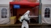 A worker wearing personal protective equipment disinfects the entrance to a residential area on lockdown due to the recent COVID-19 outbreaks in Beijing.