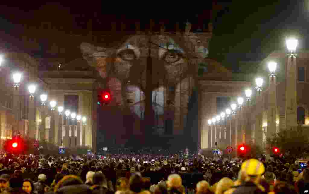 People gather to watch images projected on the facade of St. Peter&#39;s Basilica, at the Vatican, Dec. 8, 2015.