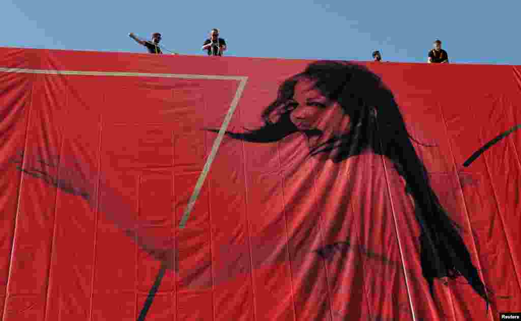 Para pekerja memasang kanvas raksasa sebagai poster resmi Festival Film Cannes, dengan gambar artis Claudia Cardinale, di Cannes, Perancis tenggara.