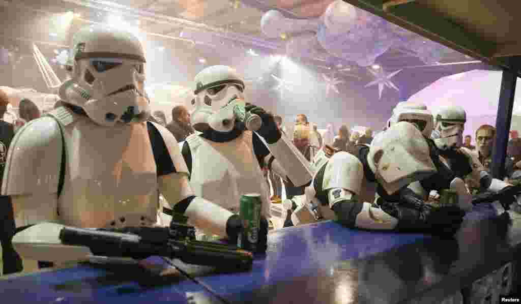 People dressed as Storm Troopers stand at a bar as they pose for a photograph holding cans of beer at the "For The Love of The Force" Star Wars fan convention in Manchester, northern England.