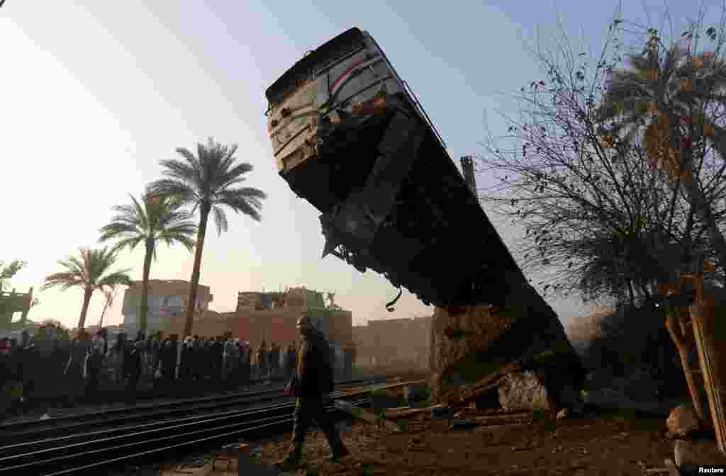 A crowd looks at the wreckage of a train crash in Beni Suef, south of Cairo, Egypt.