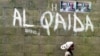 A girl walks past a wall with graffiti about the al-Qaida network in a Muslim area of the northern city of Kano, Nigeria, (File photo).