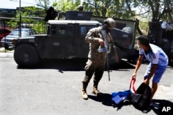 A soldier checks a man's backpack at the exit of the Las Palmas Community, a neighborhood that is supposed to be under the control of the Barrio 18 Gang in San Salvador, El Salvador, March 27, 2022.