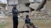 Mahmoud Madarati, 55, poses as he stands near his son whose leg and hand were amputated after sustaining injuries by what Mahmoud says was shelling from government-held areas, northern Syria, March 3, 2022. 