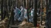 Para petugas forensik membawa kantong-kantong mayat di lokasi kuburan massal yang ditemukan di sebuah hutan pinggiran kota Izyum, Ukraina timur, 18 September 2022 (foto: dok). 
