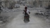 A man drives a motorcycle while carrying his weapon near damaged buildings in the northern Syrian town of al-Bab, Syria, March 1, 2017.