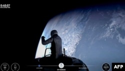 TOPSHOT - This still image taken from a SpaceX and Polaris broadcast on September 12, 2024, shows US fintech billionaire Jared Isaacman (EV1) peeking out to space from a hatch structure called "Skywalker", during the first private spacewalk performed by t