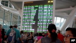 인도네시아 발리 국제공항 터미널에서 승객들이 화산 분화로 취소된 비행기 출도착 정보를 확인하고 있다.