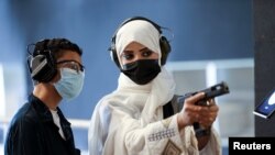 Saudi female firearm trainer, Mona Al Khurais, teaches a Saudi boy on safe usage of weapons at the Top-Gun shooting range in Riyadh, Saudi Arabia, October 28, 2021. Picture taken October 28, 2021. REUTERS/Ahmed Yosri