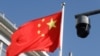 FILE - A surveillance camera overlooking a street hangs next to a Chinese flag in Beijing, China, Nov. 25, 2021. Street cameras are a primary mode of surveillance in China; more than half of the world's nearly 1 billion surveillance cameras are in China.