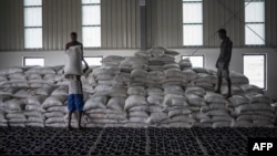 FILE - Men carry a bags of wheat to be loaded on an aid truck in a U.N. storehouse on the outskirts of Semera, Afar region, Ethiopia, May 15, 2022. 