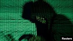 FILE - A man holds a laptop computer as cyber code is projected on him in this illustration picture taken on May 13, 2017. 