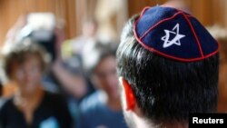 A member of Jewish community wearing a kippah talks to the media before the trial of a Syrian charged with assault at the Moabit court in Berlin, June 19, 2018.