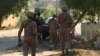 Paramilitary forces and police take cover behind a wall during an attack on the Chinese consulate, where blasts and shots are heard, in Karachi, Pakistan, Nov. 23, 2018. 