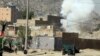 Smoke rises from a house where suspected attackers were hiding while policemen arrests two suspects, left, in Kabul, Afghanistan, Aug. 21, 2018.